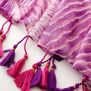 Detail of pink and purple woven scarf with golden threads and bicolor tassel fringe