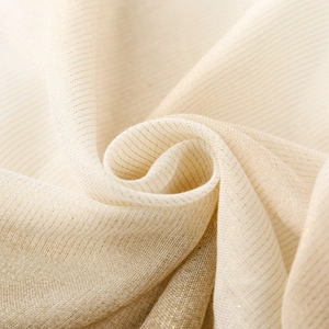 Macro detail of cream linen scarf featuring shimmering silver metallic threads and fringe