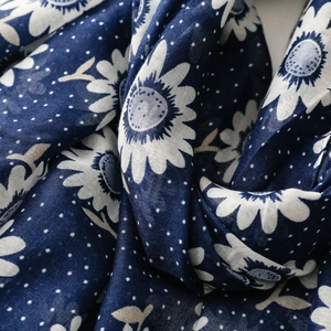Close-up of navy blue floral scarf showing soft cotton texture and white daisy prints