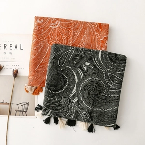 Detailed flat lay of bohemian paisley shawls with tassels in orange and black tones