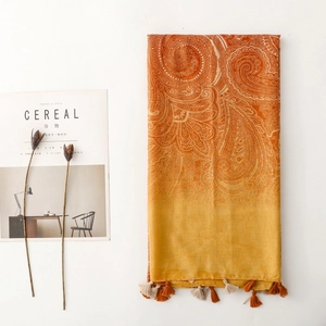 Detail of orange bohemian paisley scarf featuring intricate patterns and soft fringe tassels