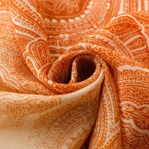 Macro shot of bohemian paisley shawl showing orange gradient texture and fine fringe detail