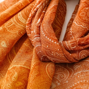 Detailed macro view of caramel orange bohemian scarf with white paisley patterns and soft texture