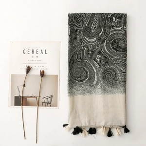 Flat lay of bohemian paisley scarf with fringe tassels beside a minimalist cereal magazine