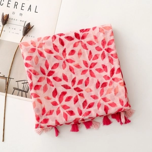 Detail of pink floral scarf with red leaf patterns and delicate fringed tassels