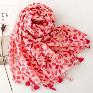 Pink shawl with red geometric print and tassel fringe shown from a 45-degree top view