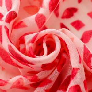 Macro detail of breathable pink scarf fabric with heart prints and fringed texture