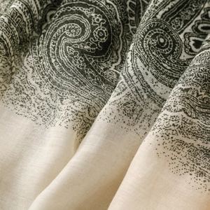 Close-up of bohemian paisley print scarf with beige and dark green fabric texture