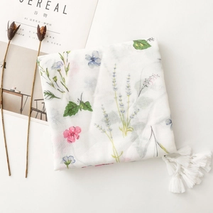 Detail of white scarf with floral lavender patterns, herringbone texture, and white tassels