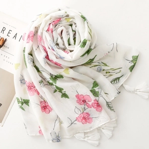 Detail of white scarf with pink floral pattern, herringbone weave, and fringe tassels