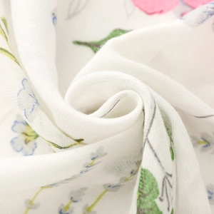 Detailed texture of white floral scarf featuring soft herringbone weave and tassel finish