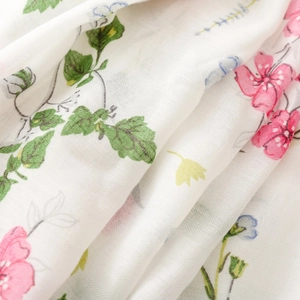Close-up of white floral scarf fabric with pink flowers and breathable cotton texture