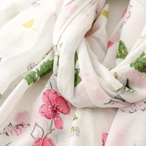 Detailed macro view of soft white scarf with pink floral prints and fringe texture