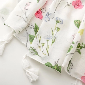 Close-up of white floral scarf with herringbone texture and delicate fringe tassels