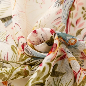 Detail of bohemian floral scarf fabric showing delicate pink blooms and soft tassels