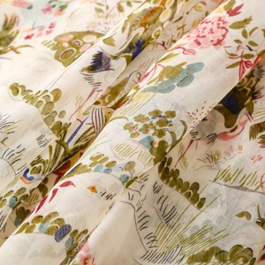 Detail of bohemian scarf showing crane and botanical prints on soft tasseled fabric