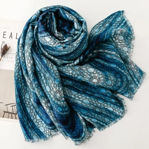 Detail of blue geometric floral printed scarf with delicate fringed edges and soft texture