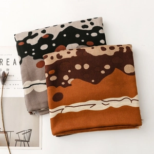 Detail of dark polka dot and caramel scarves with soft frayed edges and abstract textures