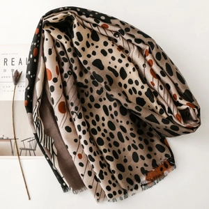 Artistic leopard print long scarf with tassels shown next to lifestyle magazine