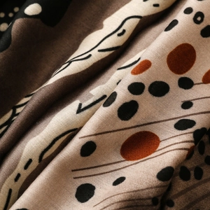 Macro detail of abstract geometric print on a soft, earthy-toned textile fabric shawl