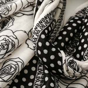 Macro view of black and white floral print scarf with rose motifs and polka dot details