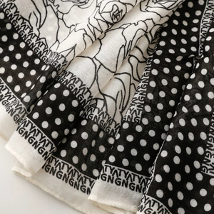 Detail of floral and polka dot print on lightweight black and white scarf fabric