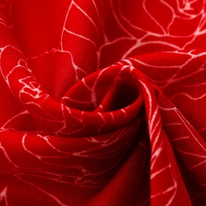 Close-up of elegant red silk scarf with detailed white floral rose patterns and twill texture