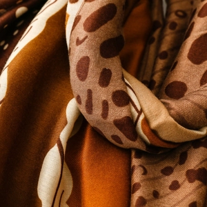 Macro detail of Earth-tone animal print scarf showing soft texture and draped silk fabric