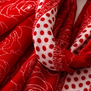 Close-up of red and white silk scarf showing rose floral patterns and dot print texture