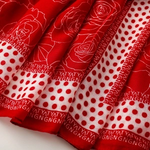 Detail of red floral scarf featuring white rose prints and polka dot border textures
