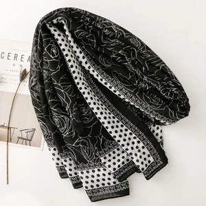 Detail of a black and white floral and polka dot silk scarf next to a lifestyle magazine