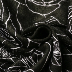 Close-up of black floral scarf with white rose line art and woven texture details