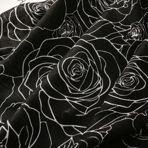 Detail of floral printed scarf with white rose line art patterns on black textile fabric