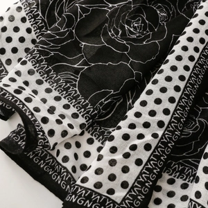 Detailed view of floral and polka dot print on lightweight black and white scarf fabric