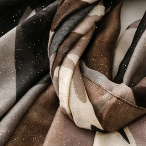 Détail macro d'une écharpe géométrique abstraite avec paillettes dorées et texture lin
