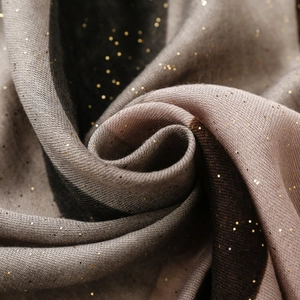 Détail d'une écharpe en dégradé doux avec paillettes dorées et tissu léger et fluide