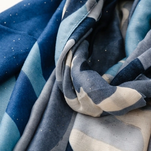 Détail de l'écharpe abstraite bleue et blanche avec texture douce et paillettes dorées