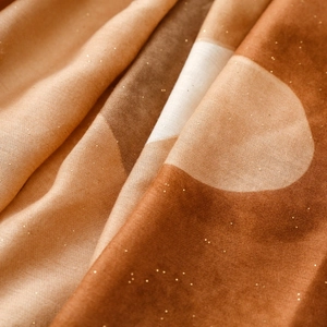 Détail macro d'une écharpe effet coton-lin avec imprimé feuille d'or et motifs géométriques