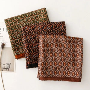 Dettaglio di scialli a motivo paisley in seta nei colori oliva, nero e caramello