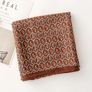 Dettaglio della sciarpa in seta paisley con bordo arrotolato accanto a una rivista moderna