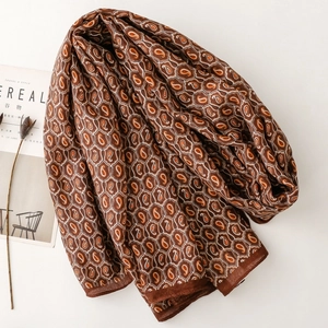 Dettaglio di sciarpa pashmina marrone con motivi paisley arancioni e decorazioni floreali