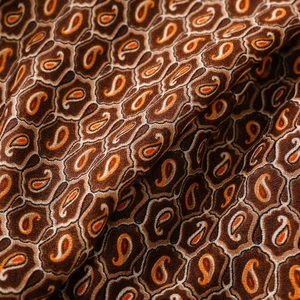 Dettaglio macro del classico motivo paisley sul tessuto della sciarpa lunga marrone