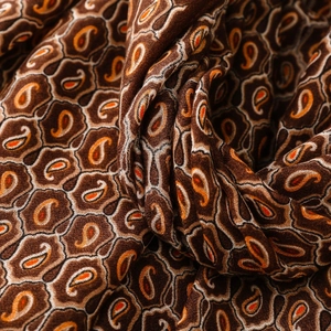 Dettaglio del motivo paisley vintage su morbida sciarpa marrone con eleganti drappeggi