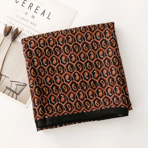 Dettaglio della sciarpa con motivo paisley e trama in seta arancione e nera chic