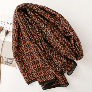 Dettaglio della sciarpa con motivo paisley, tessuto morbido e bordo nero elegante