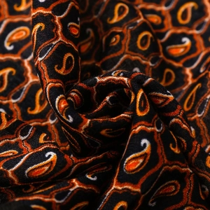 Dettaglio ravvicinato del motivo paisley arancione e bianco su sciarpa di tessuto nero