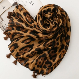 Detailed macro view of leopard print scarf fabric showing soft texture and fringe tassels