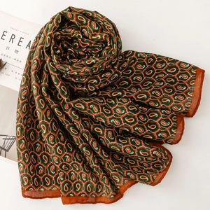 Dettaglio della sciarpa paisley verde con trama morbida e cuciture arancioni