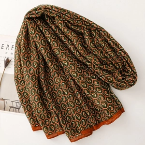 Dettaglio di una sciarpa bohémien con stampa paisley verde oliva e bordi arancioni