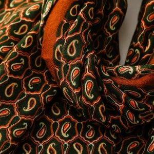 Dettaglio del morbido tessuto paisley con motivi a nido d'ape arancione e verde